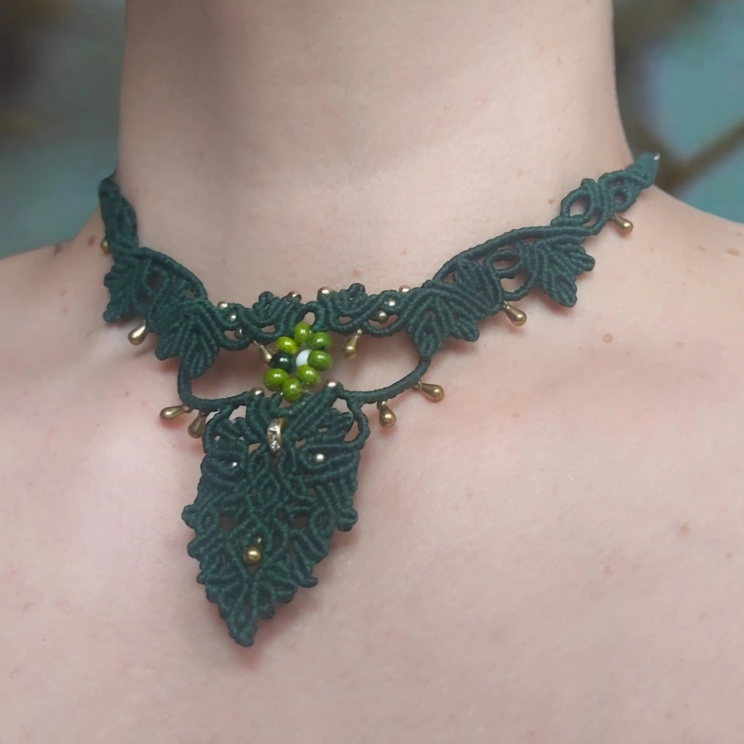 Elegant green choker necklace with gold embellishments and floral details.