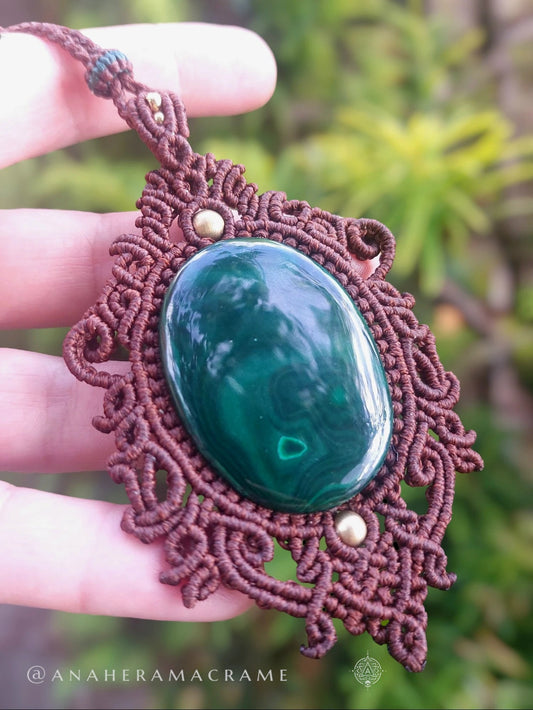 Close-up of macrame knotwork surrounding a polished green gemstone in a handmade necklace.