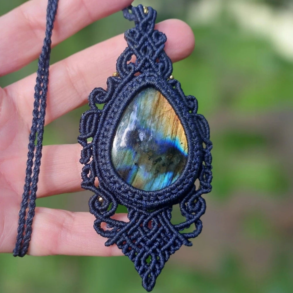 Crystal pendant made from 60ct labradorite glowing in iridescent blues, surrounded by symmetrical blue macramé knots.