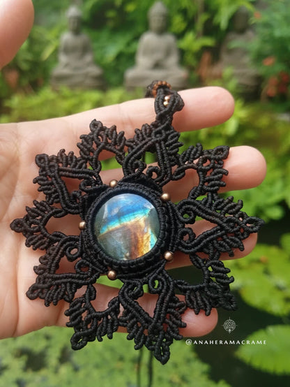 Brown lace pendant with a colorful stone held in a hand against a blurred natural background
