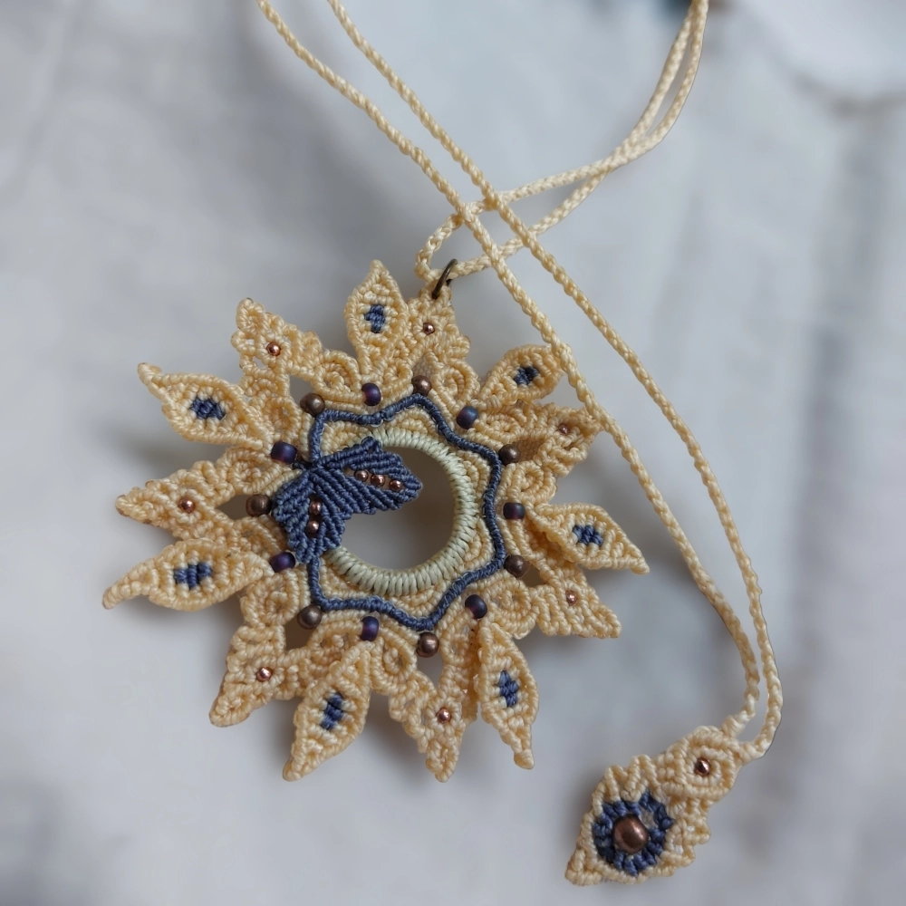 This macrame mandala necklace features a light blue leaf design and it is crafted with care using a hematite ring as its structure. The threads are woven on the ring to form a stunning pendant. The necklace has an adjustable length of approximately 56cm/22 inches, including the pendant, making it easy to customize for a comfortable fit with the help of a slide lock. 