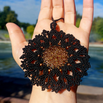 Close-up of the brass filigree pendant on the black mandala macrame necklace.