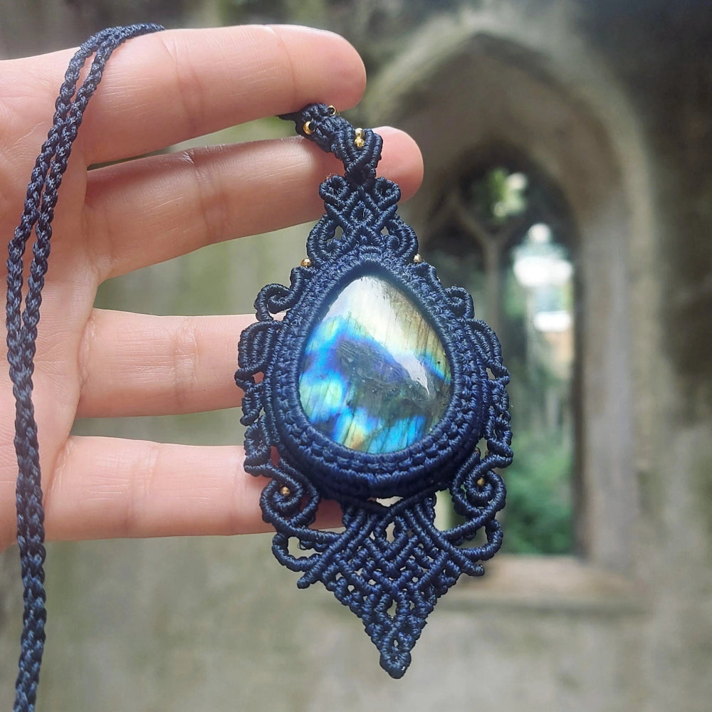 Detailed view of an artisan necklace with a large teardrop labradorite, secured in elegant blue handwoven macramé.