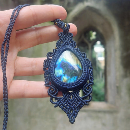 Detailed view of an artisan necklace with a large teardrop labradorite, secured in elegant blue handwoven macramé.