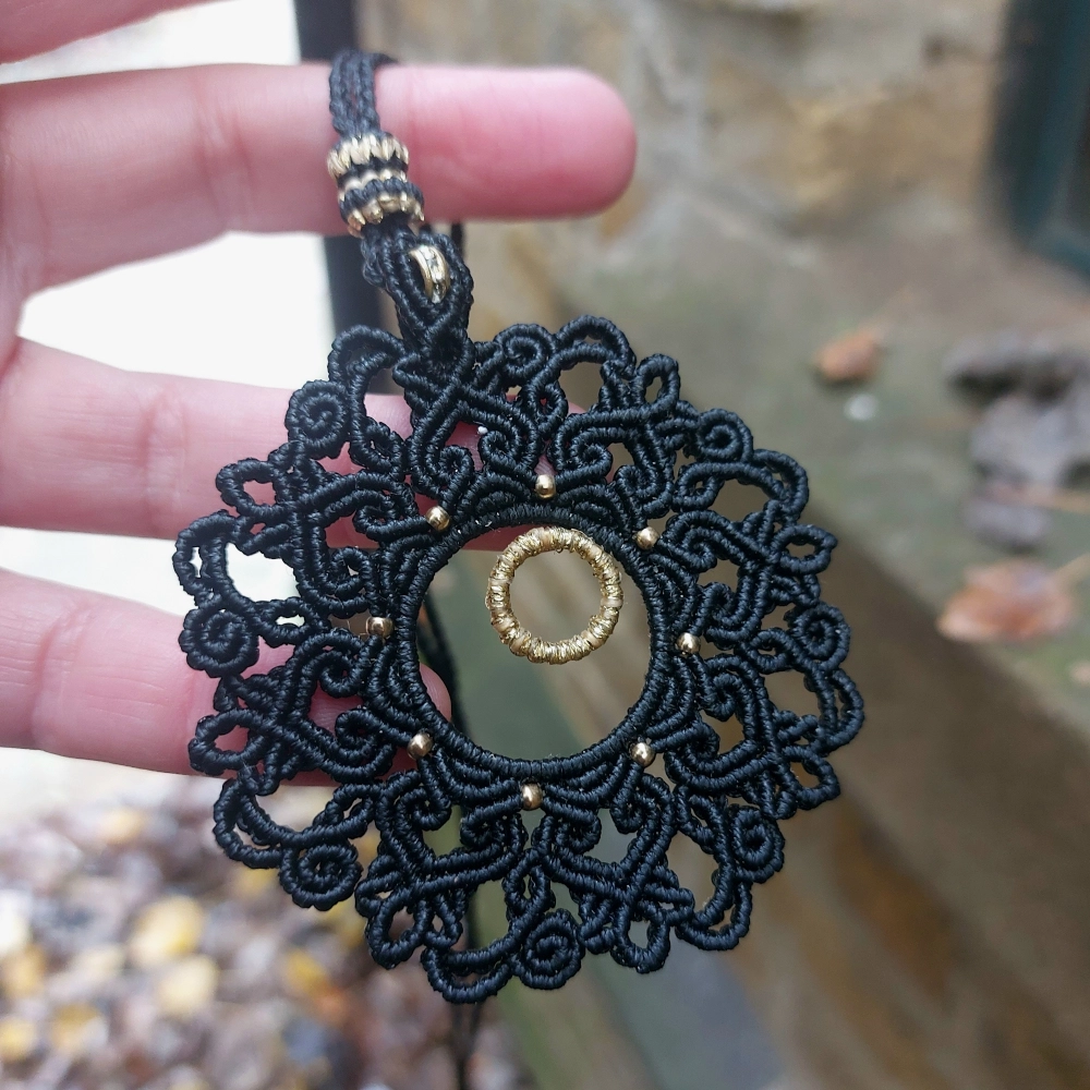 Artisan-crafted black macrame necklace with intricate mandala design and gold rondelle bead for a timeless boho look.
