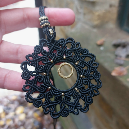 Artisan-crafted black macrame necklace with intricate mandala design and gold rondelle bead for a timeless boho look.
