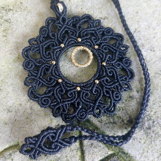 Handmade black macrame necklace with a golden rondelle bead and mandala design, perfect for bohemian and artisan jewelry enthusiasts.
